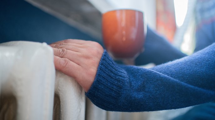 Bild zeigt Hände, die sich an einer Heizung wärmen. Es geht um das Berechnen des Gasverbrauchs von m³ in kWh.