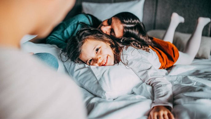 Bild zeigt eine Familie, die im Schlafzimmer herumtollt 