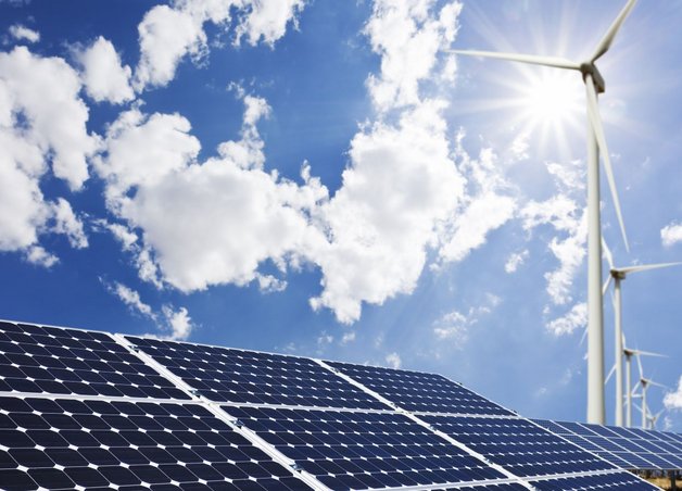 Solaranlage und Windkraftanlagen bei blauem Himmel; kombinierte Stromerzeugung aus Sonne und Wind, nachhaltig und klimafreundlich.