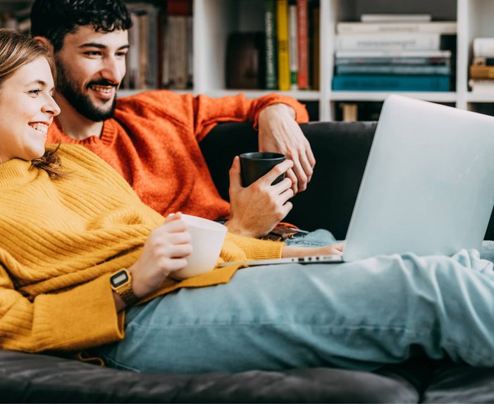 Bild mit einem Paar auf dem Sofa vor einem Notebook, Link: Angebot anfragen