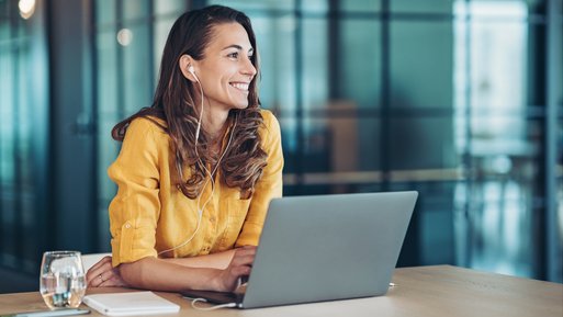 Frau am Laptop mit Kopfhörern, symbolisiert moderne Kommunikation und Anwendungen von ENTEGA Business Voice Premium mit Glasfaser.