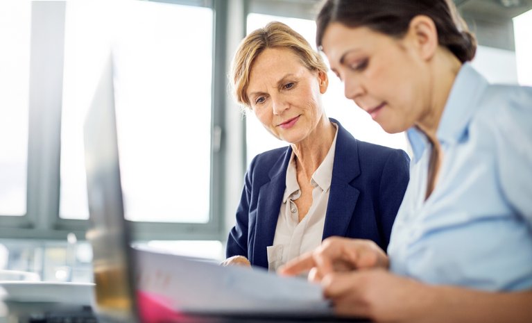"Frauen im Büro lesen gemeinsam Unterlagen, symbolisieren Zusammenarbeit im Kontext von Erdgasanwendungen für Industriekunden. "