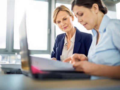 "Frauen im Büro lesen gemeinsam Unterlagen, symbolisieren Zusammenarbeit im Kontext von Erdgasanwendungen für Industriekunden. "
