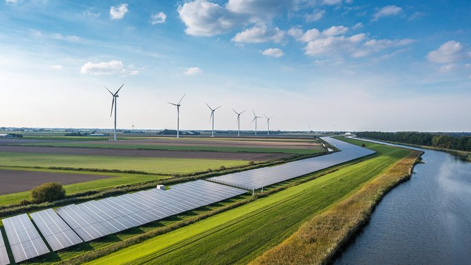 Weite Landschaft mit Solarpanels und Windturbinen entlang eines Kanals. Symbolisiert nachhaltige Energieerzeugung in der Natur.