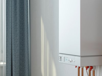 Gastherme mit Kupferrohren und Bedienfeld, Absperrventile sichtbar; Bezug zu Gastherme Kosten im hellen Innenraum.