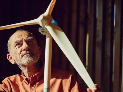 Mann steht vor Windradmodell. Stromerzeugung im Fokus als Symbol für erneuerbare Energie.