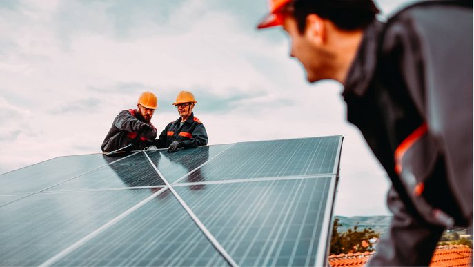 Bild zeigt drei Männer auf einem Dach bei der Installation einer Solaranlage – Thema: Solarenergie.