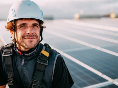 Moodbild zeigt einen Bauarbeiter vor Solarmodulen, Symbolbild zum Thema „Was ist Photovoltaik?“