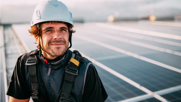 Moodbild zeigt einen Bauarbeiter vor Solarmodulen, Symbolbild zum Thema „Was ist Photovoltaik?“