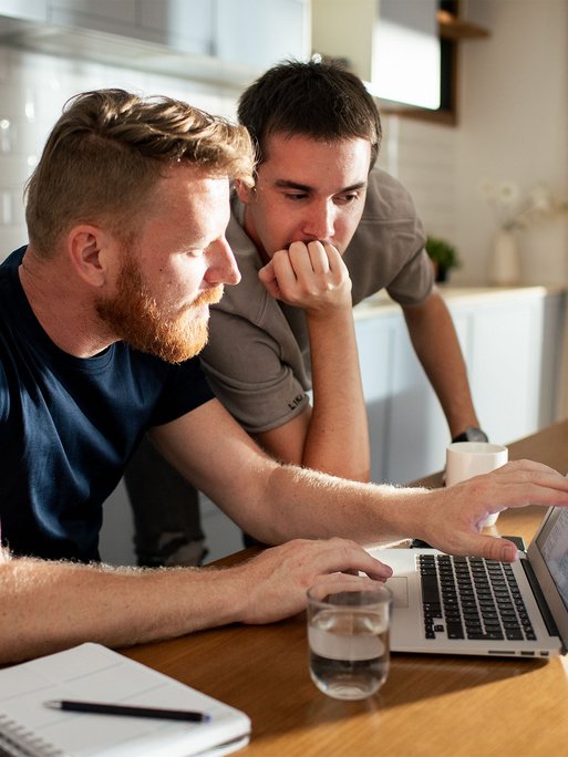 Fachleute planen gemeinsam am Laptop, Notizbuch auf dem Tisch. Experten unterstützen beim Fernwärmeumstieg.