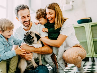 Bild zeigt eine vierköpfige Familie mit Hund in ihrem Zuhause als Symbolbild für den Gasverbrauch von vier Personen.