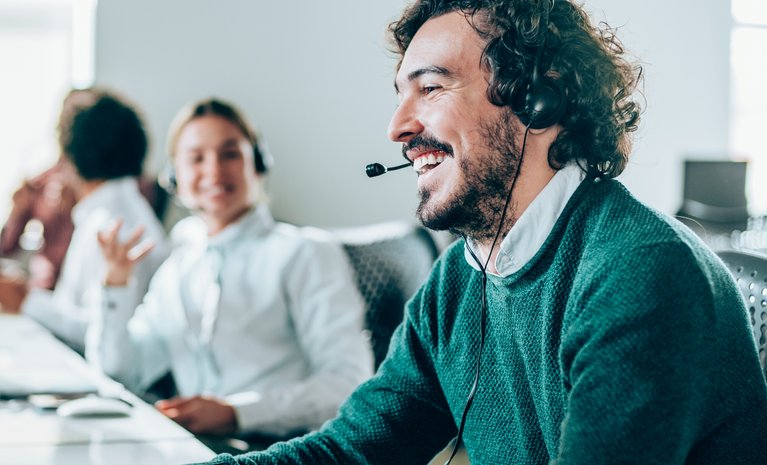 Mann mit Headset lächelt im Büro, symbolisiert hervorragende Sprachqualität von ENTEGA Business Voice Premium.
