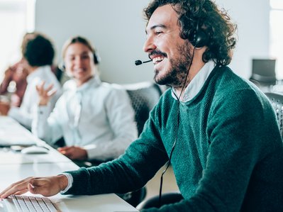 Mann mit Headset lächelt im Büro, symbolisiert hervorragende Sprachqualität von ENTEGA Business Voice Premium.