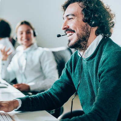 Mann mit Headset lächelt im Büro, symbolisiert hervorragende Sprachqualität von ENTEGA Business Voice Premium.