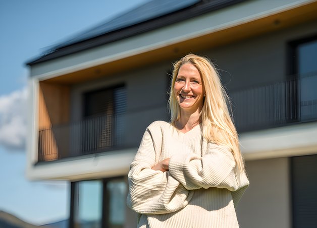 Bild zeigt lächelnde Frau vor einem Haus – Thema: Marktlokations-ID.