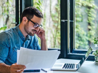 Ein Mann am Schreibtisch prüft Belege an seinem Laptop. Er informiert sich über eine Stromanbieter-Insolvenz.