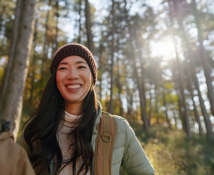 Zwei lächelnde Frauen im sonnigen Wald, symbolisieren zugänglichen Klimaschutz und Teilnahme an der Energiewende.