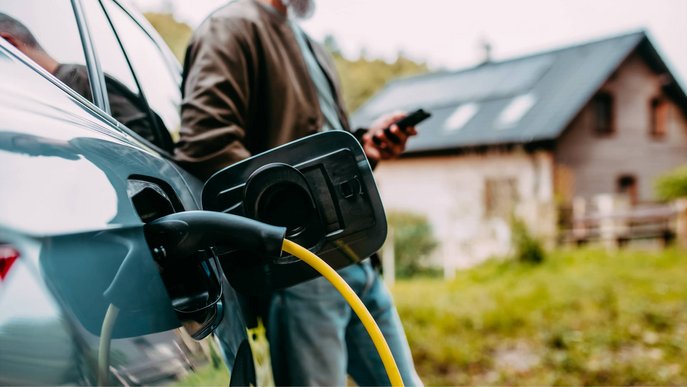 Bild zeigt einen Mann, der sein Elektroauto mit Solarstrom tankt