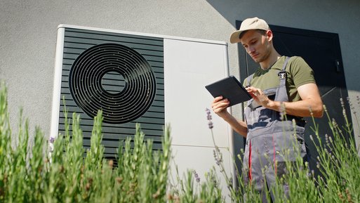 Techniker prüft Wärmepumpe mit Tablet, im Vordergrund Lavendel. Hebt spezialisierte Heizstrom-Tarife von ENTEGA für Wärmepumpen hervor.