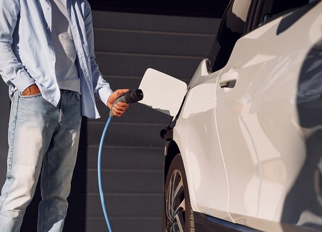 Bild zeigt Person beim Laden des Elektroautos. Es geht um die Wallbox-Förderung und verschiedene Zuschüsse. 