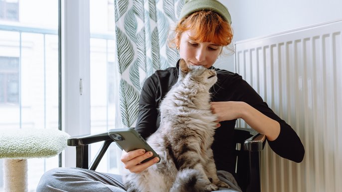 Bild zeigt eine Frau mit Katze vor der Heizung – wichtig, den Gaszähler regelmäßig abzulesen, um den Verbrauch im Blick zu behalten.