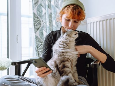 Bild zeigt eine Frau mit Katze vor der Heizung – wichtig, den Gaszähler regelmäßig abzulesen, um den Verbrauch im Blick zu behalten.