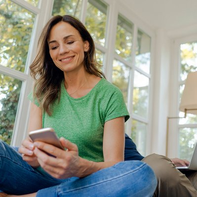 Person mit Smartphone in entspannter Atmosphäre, symbolisiert schnelle Hilfe bei Internet- und Telefonfragen.