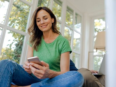 Person mit Smartphone in entspannter Atmosphäre, symbolisiert schnelle Hilfe bei Internet- und Telefonfragen.