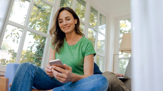 Person mit Smartphone in entspannter Atmosphäre, symbolisiert schnelle Hilfe bei Internet- und Telefonfragen.