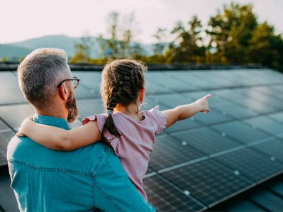 Bild zeigt Mann mit Kind vor einer Solaranlage