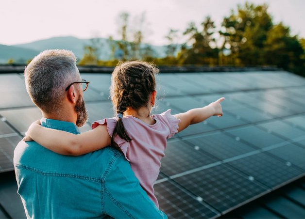 Bild zeigt Mann mit Kind vor einer Solaranlage