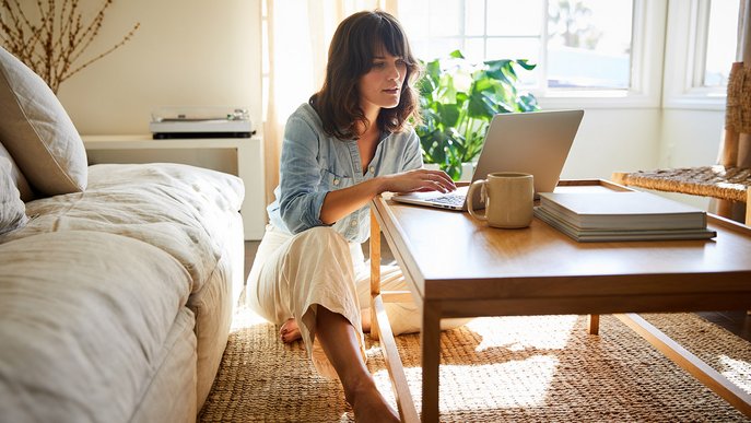 Frau arbeitet am Laptop in hellen Wohnzimmer. Symbolisiert einfachen Kündigungsprozess für ENTEGA Festnetz und Internet.