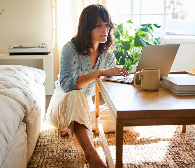 Frau arbeitet am Laptop in hellen Wohnzimmer. Symbolisiert einfachen Kündigungsprozess für ENTEGA Festnetz und Internet.