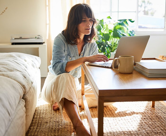 Frau arbeitet am Laptop in hellen Wohnzimmer. Symbolisiert einfachen Kündigungsprozess für ENTEGA Festnetz und Internet.