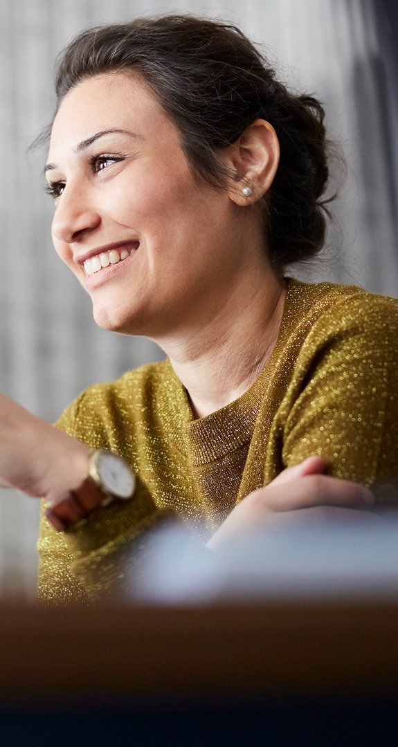 Lächelnde Frau in goldfarbenem Pullover, symbolisiert Zufriedenheit und Einfachheit beim schnellen Ökostromwechsel.