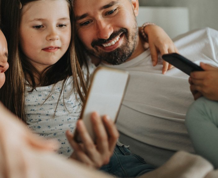 Eltern und Kinder genießen Zeit mit einem Smartphone. Symbolisiert verschiedene Tarife von ENTEGA für Singles bis Großfamilien.