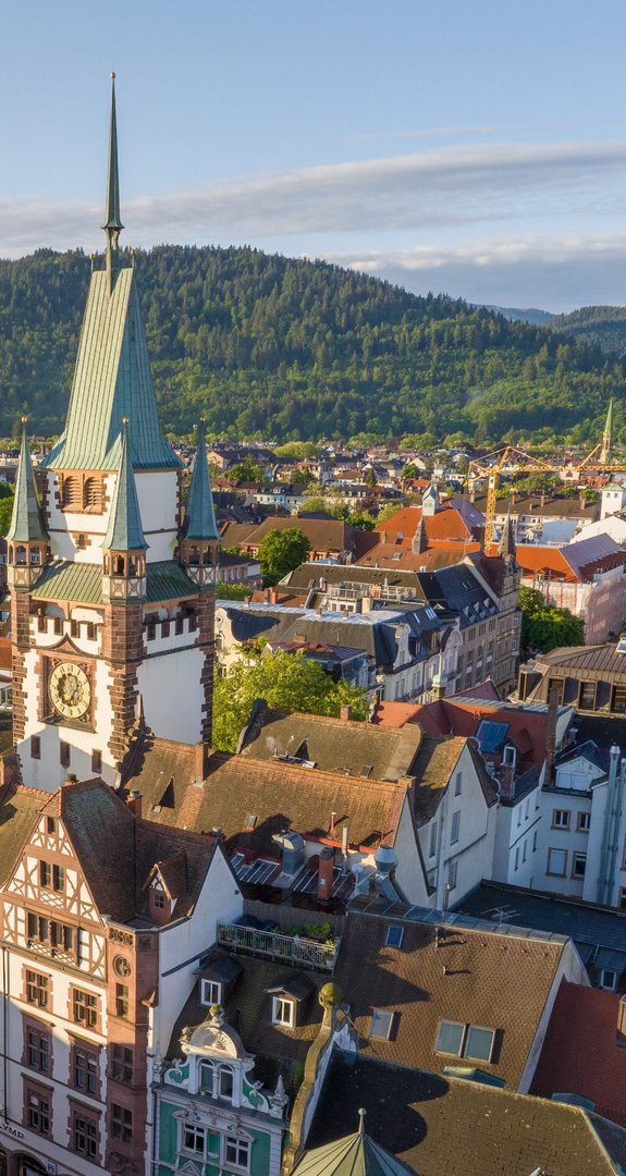 Historischer Stadtturm in Freiburg vor grünen Schwarzwaldhügeln, nachhaltige Energieversorgung durch Ökostrom Freiburg.