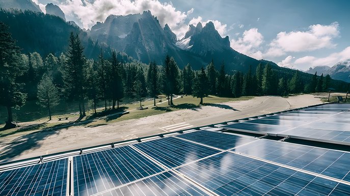 Bild zeigt Solaranlage mit Bäumen und Bergen im Hintergrund – Thema: Wirkungsgrad einer Solarzelle.