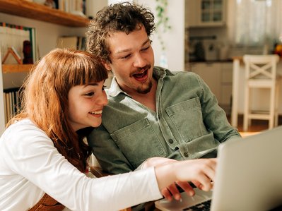 Zwei Personen vergleichen am Laptop Daten zum Stromverbrauch 2 Personen Haushalt, moderne Wohnung, bewusster Umgang mit Energie.