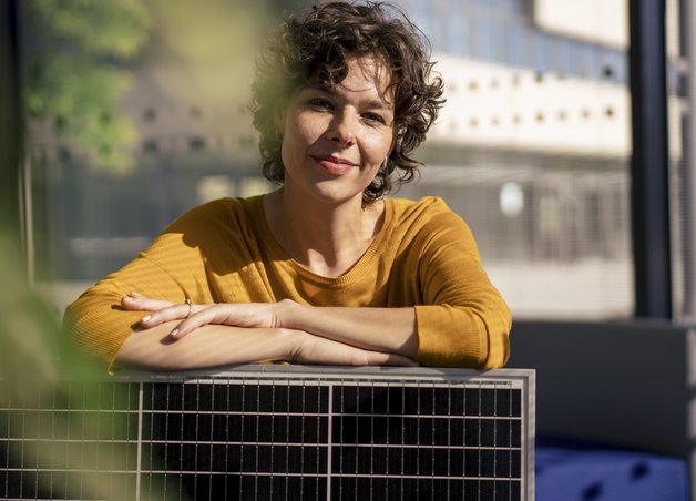 Bild zeigt eine Frau, die sich auf einem Solarmodul abstützt – Solaranlagen werden nicht nur beliebter, in vielen Fällen sind sie inzwischen sogar Pflicht.