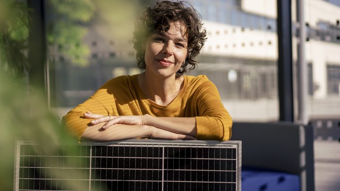 Bild zeigt eine Frau, die sich auf einem Solarmodul abstützt – Solaranlagen werden nicht nur beliebter, in vielen Fällen sind sie inzwischen sogar Pflicht.