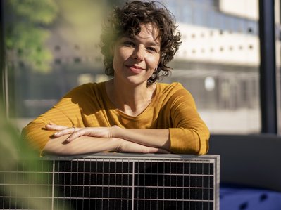 Bild zeigt eine Frau, die sich auf einem Solarmodul abstützt – Solaranlagen werden nicht nur beliebter, in vielen Fällen sind sie inzwischen sogar Pflicht.