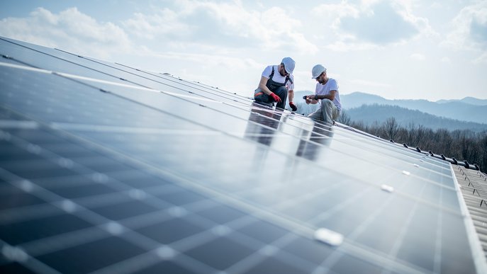 Montage von Solarmodulen durch zwei Personen auf einem Dach. Effiziente Nutzung von Photovoltaik erfordert sorgfältige Planung vor dem Kauf.