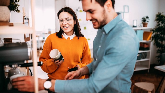 Bild zeigt eine Frau und einen Mann an einem Kaffeevollautomat in der Büroküche
