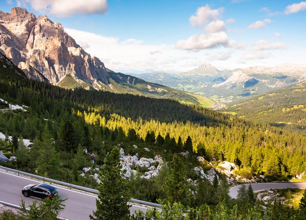 Schwarzer Pkw fährt auf kurvenreicher Bergstraße; natürliche Umgebung betont Elektroauto Ökobilanz im alpinen Kontext.