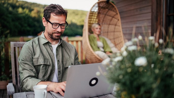 Mann in grünem Hemd, arbeitet auf Terrasse am Laptop. Symbolisiert bequeme Verwaltung der ENTEGA Zahlungsoptionen.