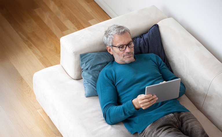 Mann mit Tablet auf Sofa, informiert sich über ENTEGA Kündigungsdetails und Vorteile.