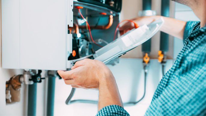 Bild zeigt einen Installateur bei der Wartung einer Gastherme 