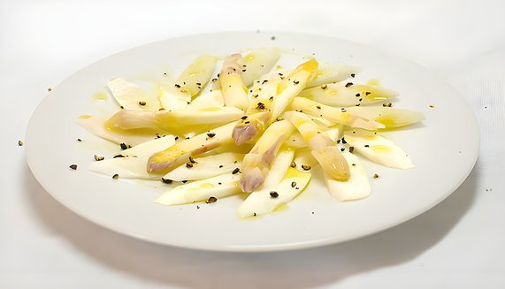 Rohe Spargelstücke auf Teller, leicht mit Pfeffer bestreut. Frühlingsgericht, frisch und knackig.
