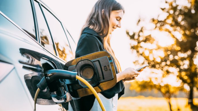 Bild zeigt eine Frau, die ihr Elektroauto auflädt.